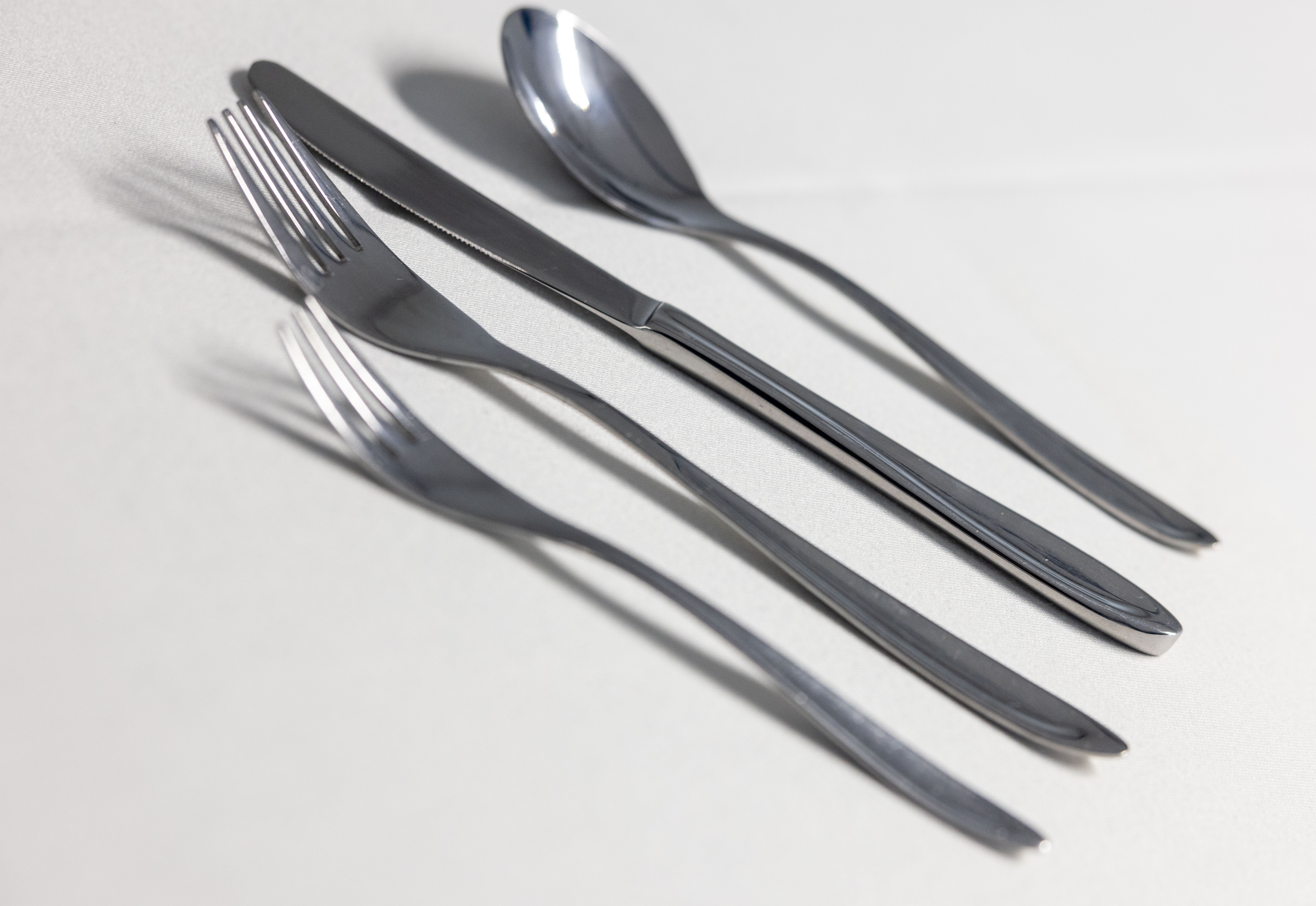 Eight shirts arranged on table in black, olive, grey, blue, white, red, mustard, and green.