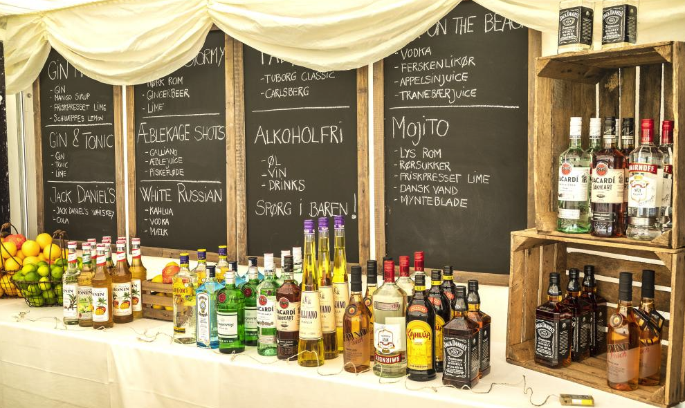 Eight shirts arranged on table in black, olive, grey, blue, white, red, mustard, and green.