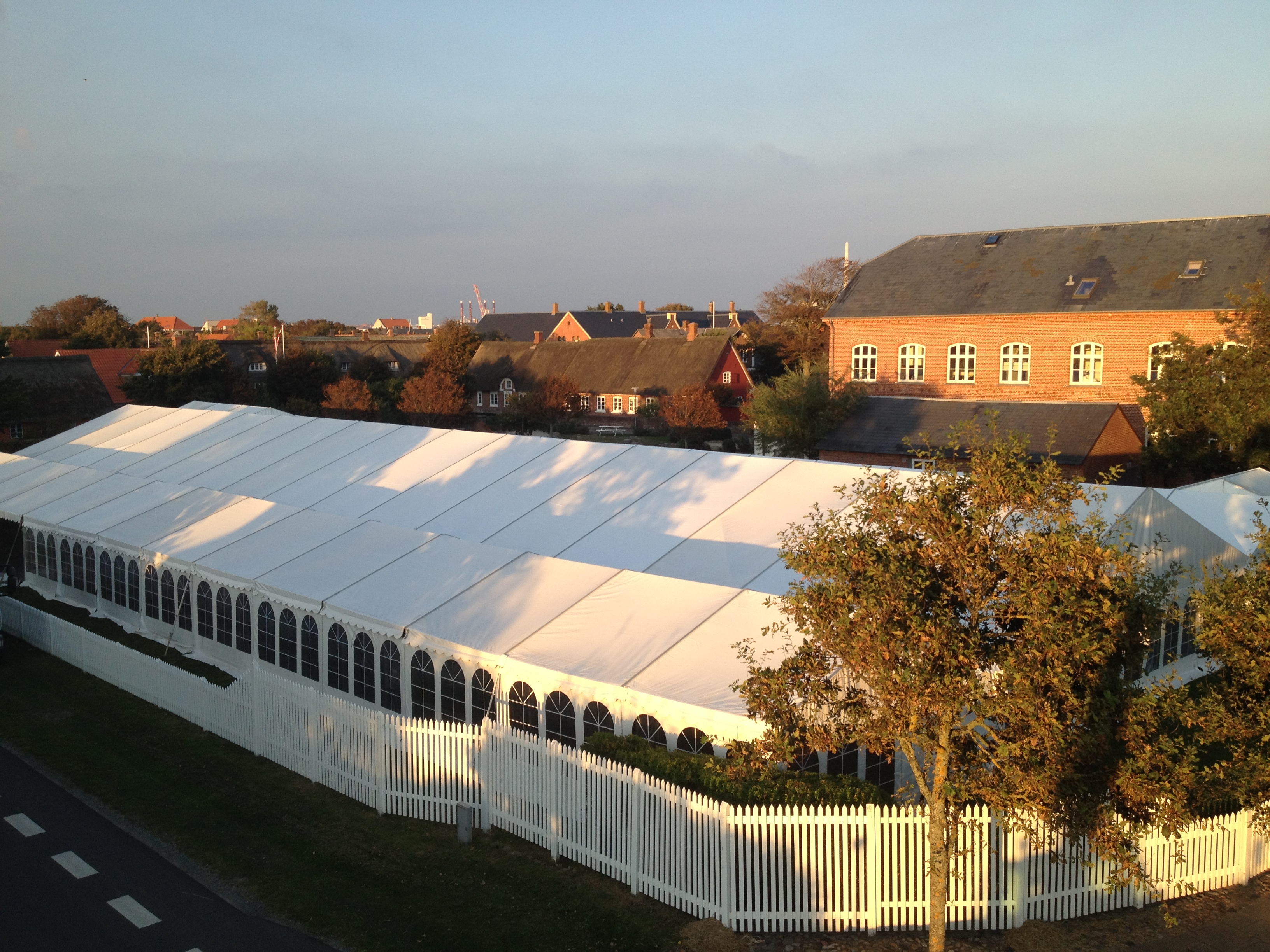 Eight shirts arranged on table in black, olive, grey, blue, white, red, mustard, and green.