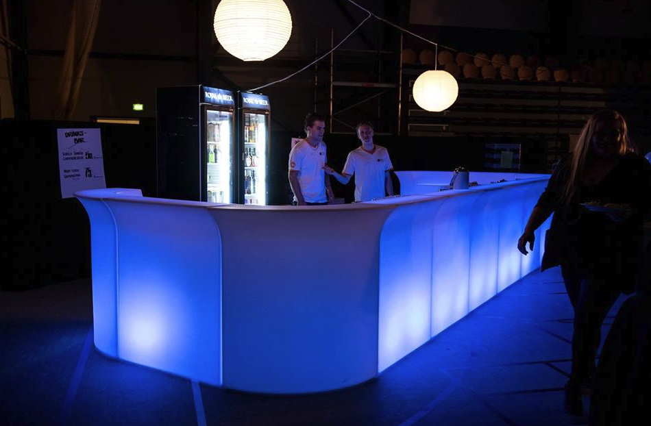 Eight shirts arranged on table in black, olive, grey, blue, white, red, mustard, and green.