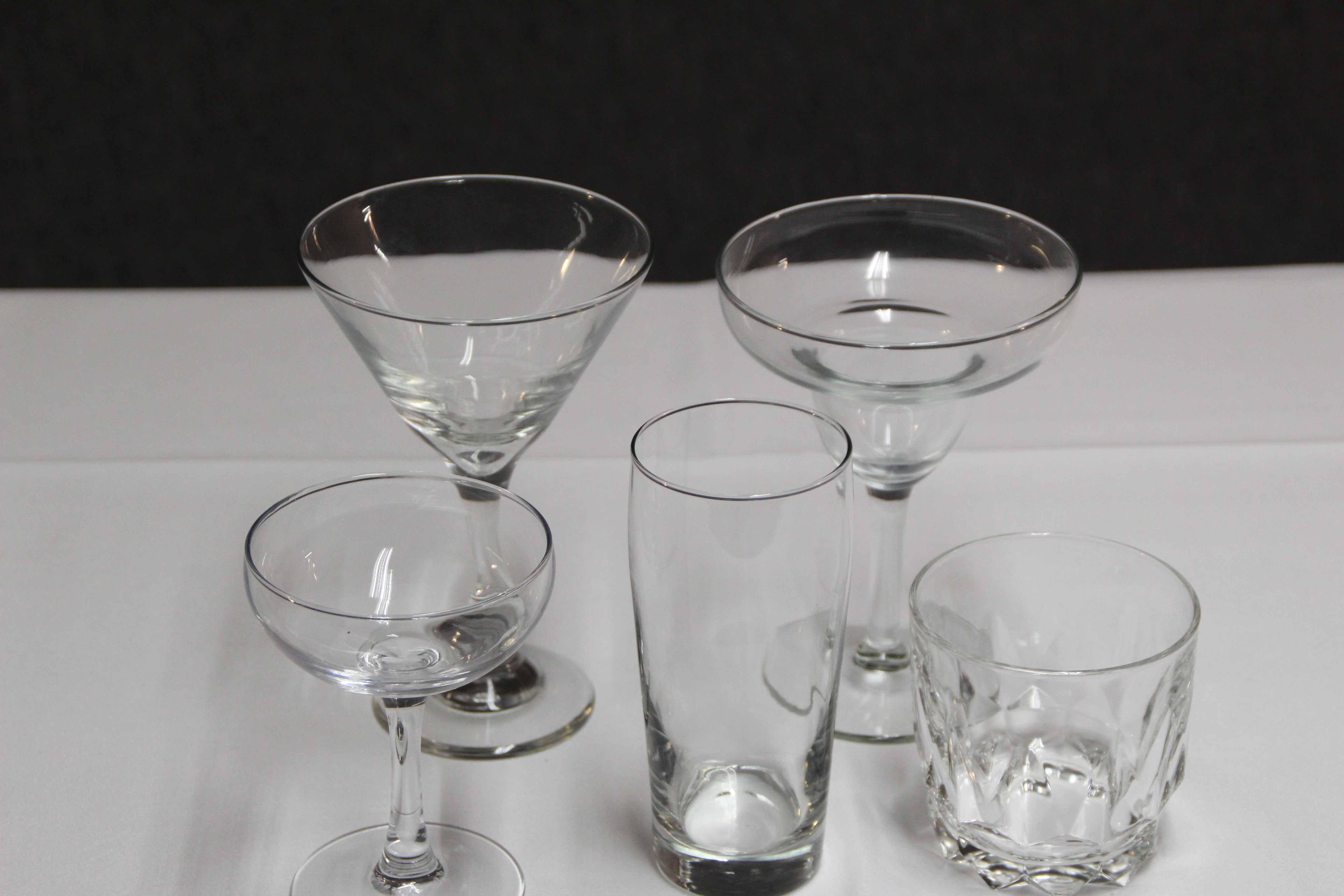 Eight shirts arranged on table in black, olive, grey, blue, white, red, mustard, and green.